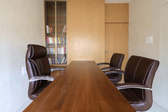 Looking down the length of the same table to a glass-fronted bookcase set into a wood-grain wall.